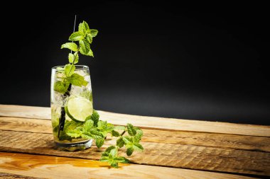 limon ve nane ile lezzetli Mojito cam siyah bir zemin üzerine ahşap bir masa yaprak