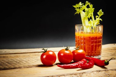 sulu kırmızı içecek bloody mary yeşil kereviz ve kırmızı biber ve domates ahşap bir masa üzerinde bir parça ile