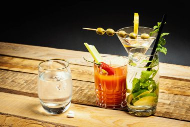Martini ve bloody mary içecek ve ahşap bir masa üzerinde su ve akşamdan kalma hap
