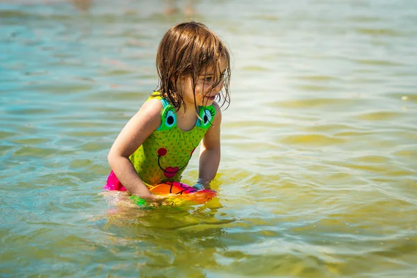 küçük kız yaz aylarında deniz renkli bir top oynamaktan