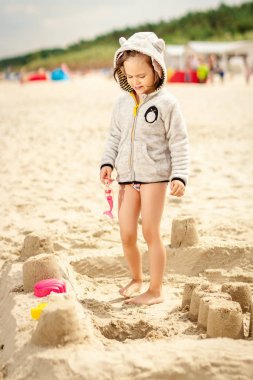 Yaz aylarında bir bebek plajda kum üzerinde oynarken küçük sevimli kız
