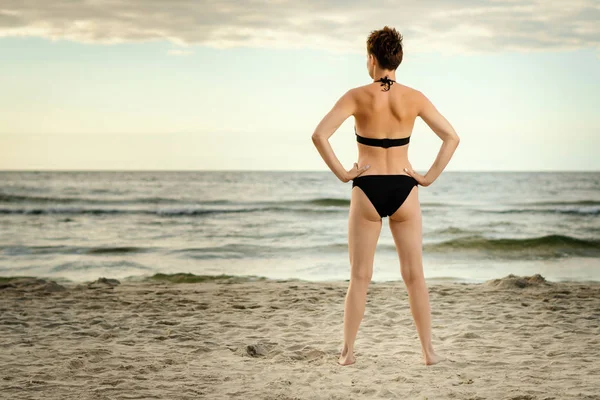 güzel kadın bir siyah mayo gün batımında sahilde denizde arıyor