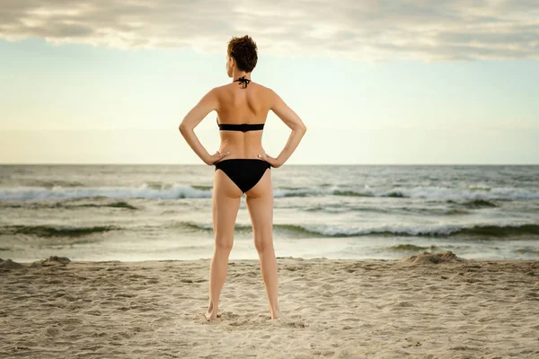 güzel kadın bir siyah mayo gün batımında sahilde denizde arıyor