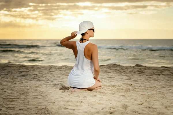 Hermosa Mujer Camisa Sentada Playa Sosteniendo Una Gorra Atardecer —  Fotos de Stock