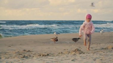 iki sevimli küçük kız çalışan ve'nde yaz günbatımı kum plajındaki ördek besleme