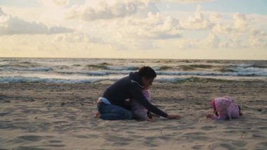 Anne ve iki kızı yaz aylarında günbatımı kum plaj üzerinde yapmaya çalışıyorsun