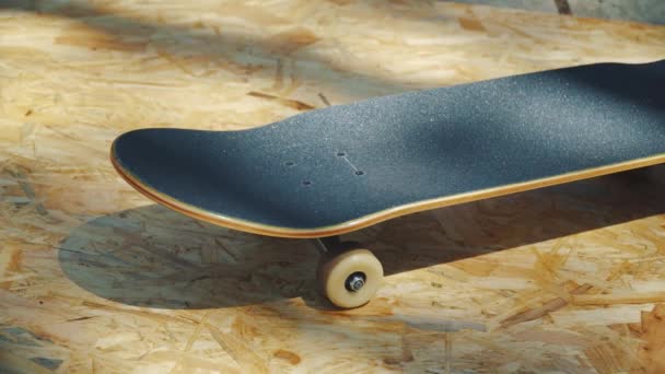 Skateboard με λευκό τροχούς σε ένα ξύλινο υπόβαθρο σε ένα skatepark — Αρχείο Βίντεο