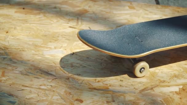 Skateboard with white wheels on a wooden background in a skatepark — Stock Video