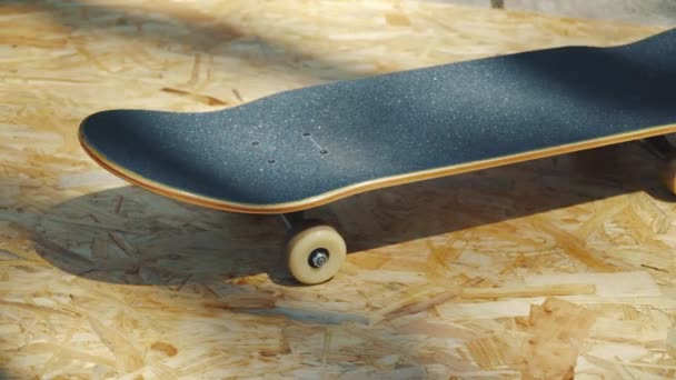 一个新的滑板与白色车轮在一个木质的背景在夏天的 Skatepark 的看法 — 图库视频影像