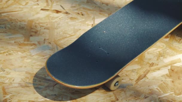 Skateboard mit weißen Rädern auf einem hölzernen Hintergrund in einem Skatepark — Stockvideo