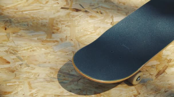 Skateboard met witte wielen op een houten achtergrond in een skatepark — Stockvideo