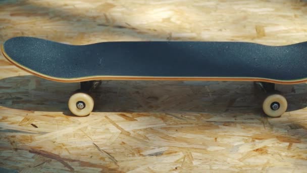 Skateboard with white wheels on a wooden background in a skatepark — Stock Video