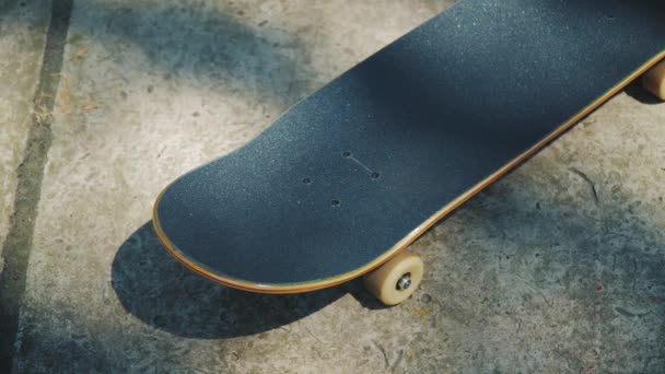 Monopatín sobre un fondo de hormigón en un skatepark en el verano — Vídeos de Stock