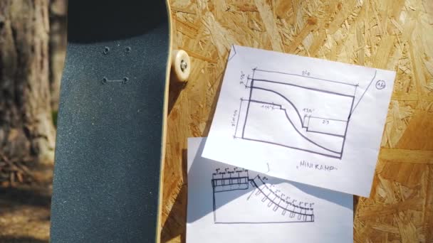 Скейтборд на деревянном фоне с планами минирампа в скейтпарке — стоковое видео