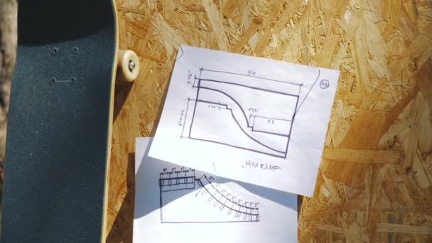 Σκέιτμπορντ σε ξύλινα φόντο με σχέδια για ένα miniramp σε ένα skatepark — Αρχείο Βίντεο