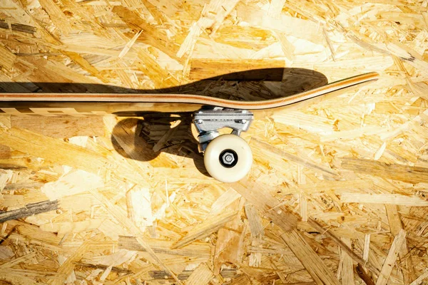 Skateboard with white wheels on a wooden background in a skatepark — Stock Photo, Image