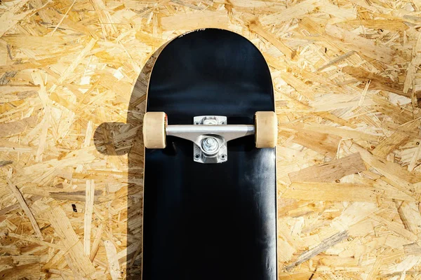 Skateboard with white wheels on a wooden background in a skatepark — Stock Photo, Image