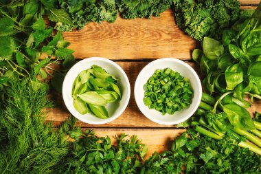 yeşil sebze ve ahşap bir masa üzerinde kase içinde baharatlar