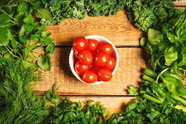 Зелені овочеві трави і помідори на дерев'яному столі — стокове фото