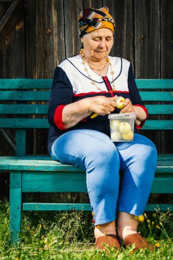 Yaşlı kadın bir bankta oturan ve yeşil elma kesme