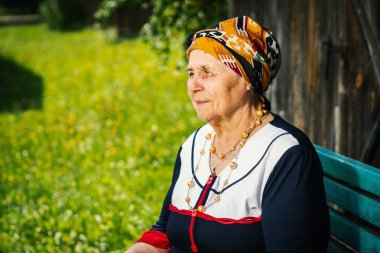 Yaşlı kadın bir tezgah ve bir fotoğraf için poz oturuyor