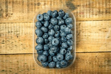 ahşap bir masa üzerinde yaban mersini ile bir konteyner