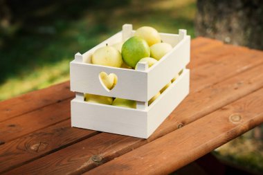 ahşap bir masa üzerinde yeşil lezzetli elma ile beyaz kutu