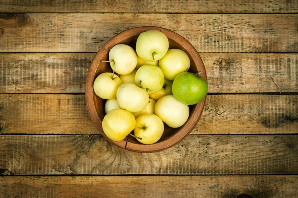 Heerlijke groene appels in een kom op een oud houten tafel — Stockfoto