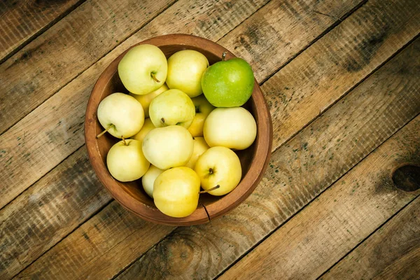 Heerlijke groene appels in een kom op een oud houten tafel — Stockfoto