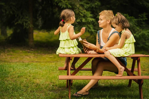 Mom and two adorable daughters talk to each other in the summer forest — Stock Photo, Image