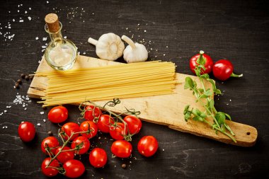 malzemeler için pişirme oluşan domates, sarımsak, tuz, yemek zeytin biber ve makarna üzerine siyah bir tablo