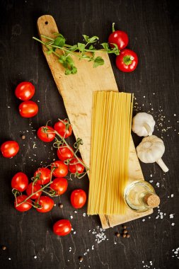malzemeler için pişirme oluşan domates, sarımsak, tuz, yemek zeytin biber ve makarna üzerine siyah bir tablo