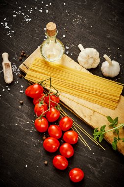 malzemeler için pişirme oluşan domates, sarımsak, tuz, yemek zeytin biber ve makarna üzerine siyah bir tablo