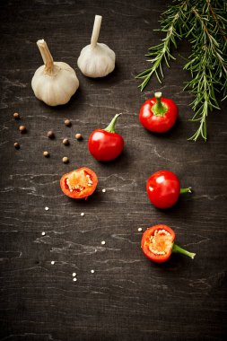 taze ve baharatlı kırmızı biber, sarımsak ve biberiye siyah ahşap bir masa üzerinde