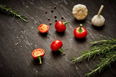 taze ve baharatlı kırmızı biber, sarımsak ve biberiye siyah ahşap bir masa üzerinde