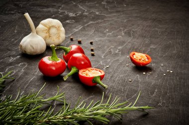 taze ve baharatlı kırmızı biber, sarımsak ve biberiye siyah ahşap bir masa üzerinde