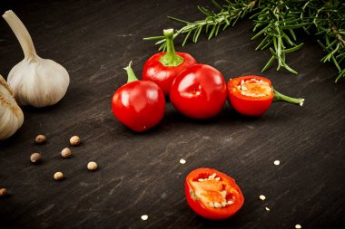 taze ve baharatlı kırmızı biber, sarımsak ve biberiye siyah ahşap bir masa üzerinde