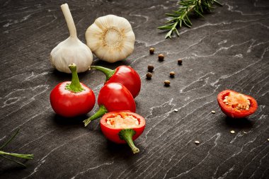 taze ve baharatlı kırmızı biber, sarımsak ve biberiye siyah ahşap bir masa üzerinde