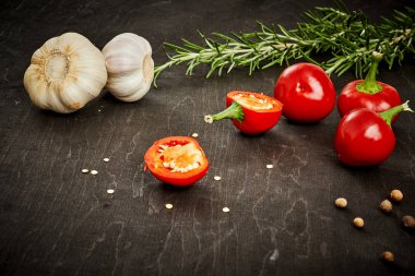 taze ve baharatlı kırmızı biber, sarımsak ve biberiye siyah ahşap bir masa üzerinde