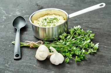 lezzetli ve kremalı taze patates püresi siyah bir tabloda gümüş bir tencerede maydanoz serpilir