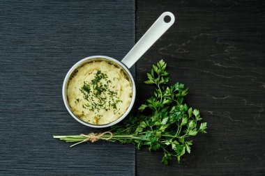 lezzetli ve kremalı taze patates püresi siyah bir tabloda gümüş bir tencerede maydanoz serpilir