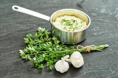 lezzetli ve kremalı taze patates püresi siyah bir tabloda gümüş bir tencerede maydanoz serpilir