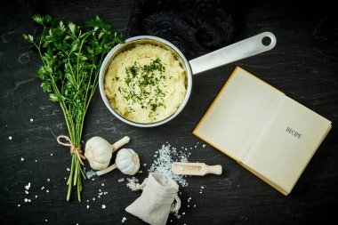 Gümüş pot ile lezzetli bir tarif kitabı siyah ahşap bir masa üzerinde yanında saf