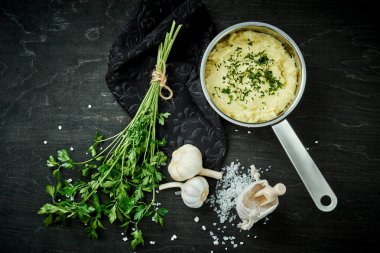 lezzetli ve kremalı taze patates püresi siyah bir tabloda gümüş bir tencerede maydanoz serpilir