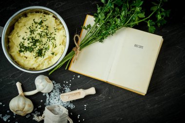 Gümüş pot ile lezzetli bir tarif kitabı siyah ahşap bir masa üzerinde yanında saf