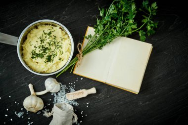 Gümüş pot ile lezzetli bir tarif kitabı siyah ahşap bir masa üzerinde yanında saf