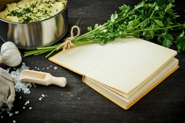 Gümüş pot ile lezzetli bir tarif kitabı siyah ahşap bir masa üzerinde yanında saf