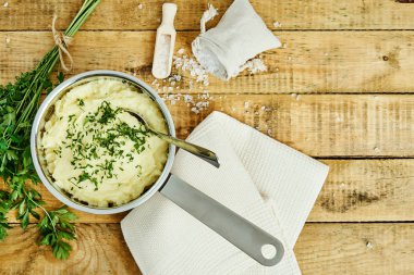 lezzetli ve kremalı taze patates püresi ahşap bir masa üzerinde gümüş bir tencerede maydanoz serpilir