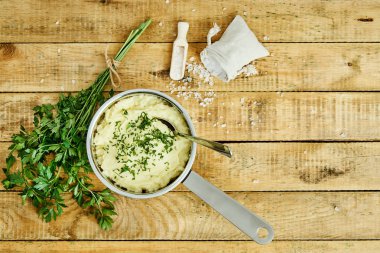 lezzetli ve kremalı taze patates püresi ahşap bir masa üzerinde gümüş bir tencerede maydanoz serpilir