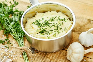 lezzetli ve kremalı taze patates püresi ahşap bir masa üzerinde gümüş bir tencerede maydanoz serpilir